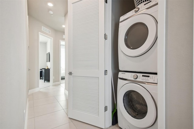 washroom featuring stacked washing maching and dryer and light tile patterned floors