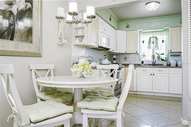 kitchen with white cabinetry, backsplash, light tile patterned floors, crown molding, and decorative light fixtures