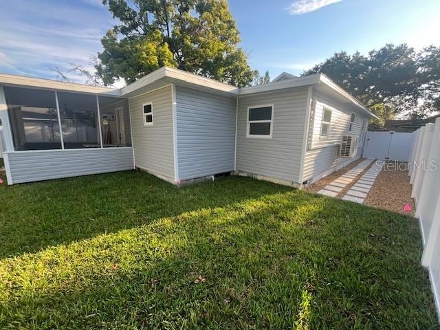 rear view of property featuring a sunroom and a yard