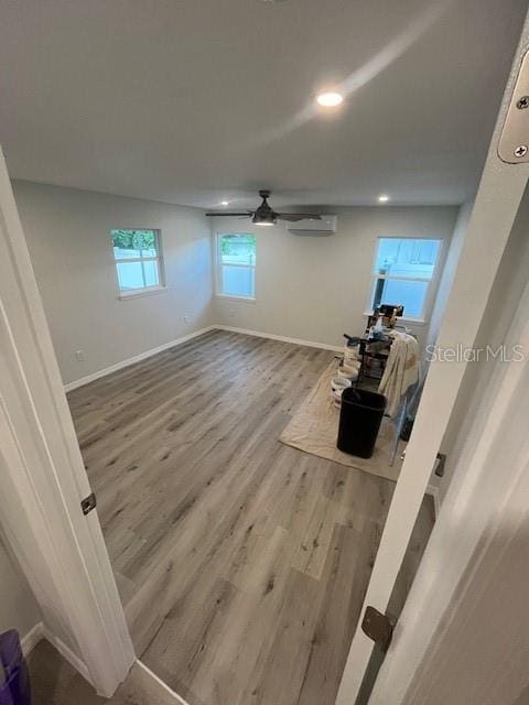 interior space featuring wood-type flooring, a wall mounted AC, and ceiling fan