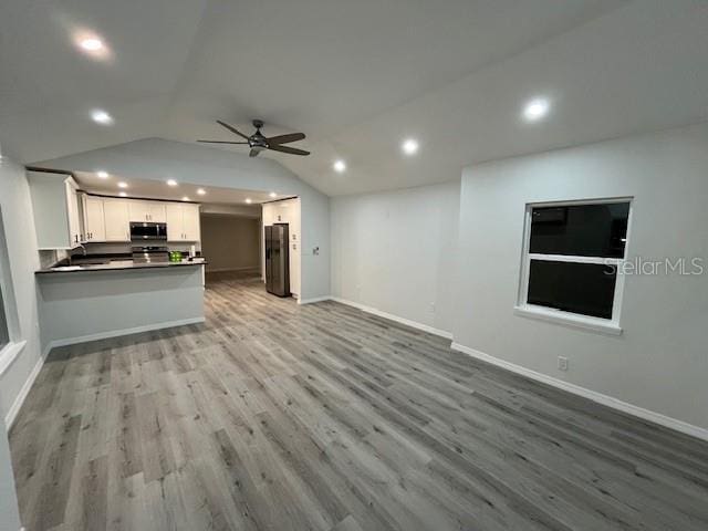 unfurnished living room with ceiling fan, light wood-type flooring, and lofted ceiling