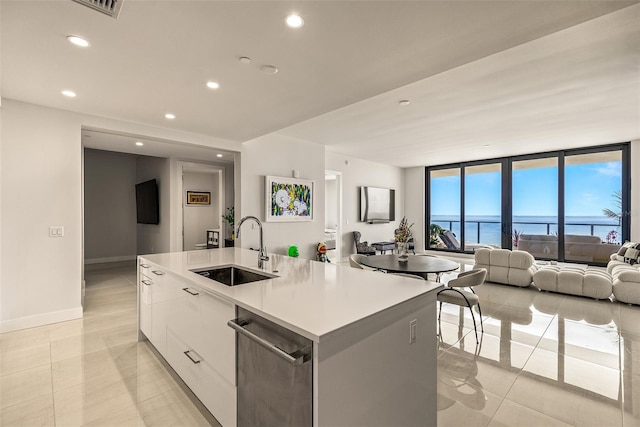 kitchen with an island with sink, light tile patterned flooring, sink, white cabinetry, and dishwasher