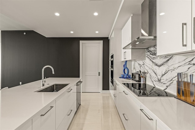 kitchen featuring white cabinets, sink, wall chimney range hood, appliances with stainless steel finishes, and backsplash