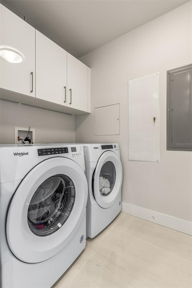 laundry room with light tile patterned flooring, electric panel, washing machine and dryer, and cabinets