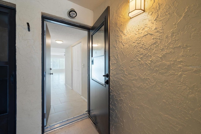 corridor featuring tile patterned flooring and a textured ceiling