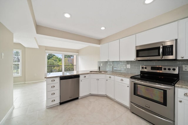 kitchen with white cabinets, light stone countertops, appliances with stainless steel finishes, and tasteful backsplash