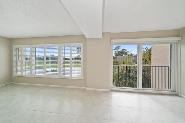 tiled empty room with a textured ceiling and a wealth of natural light