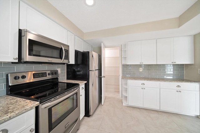 kitchen featuring stainless steel appliances, light tile patterned floors, light stone counters, decorative backsplash, and white cabinets