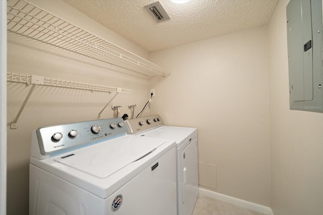 washroom featuring washing machine and dryer, a textured ceiling, and electric panel