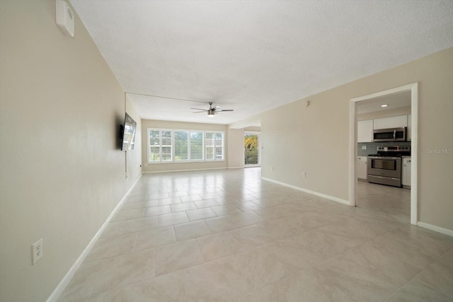 spare room featuring ceiling fan, light tile patterned floors, and a textured ceiling