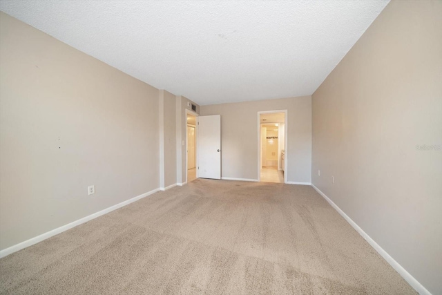 unfurnished bedroom with light carpet, a textured ceiling, and connected bathroom