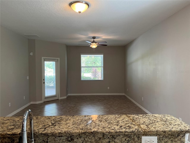 spare room featuring a textured ceiling, ceiling fan, and dark tile patterned flooring