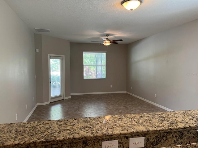 unfurnished room with dark tile patterned floors, ceiling fan, and a textured ceiling