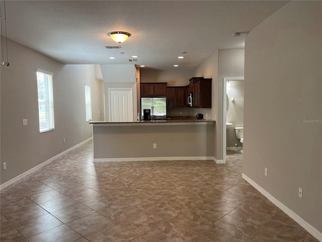 kitchen with dark brown cabinets, a textured ceiling, light tile patterned floors, and stainless steel fridge with ice dispenser