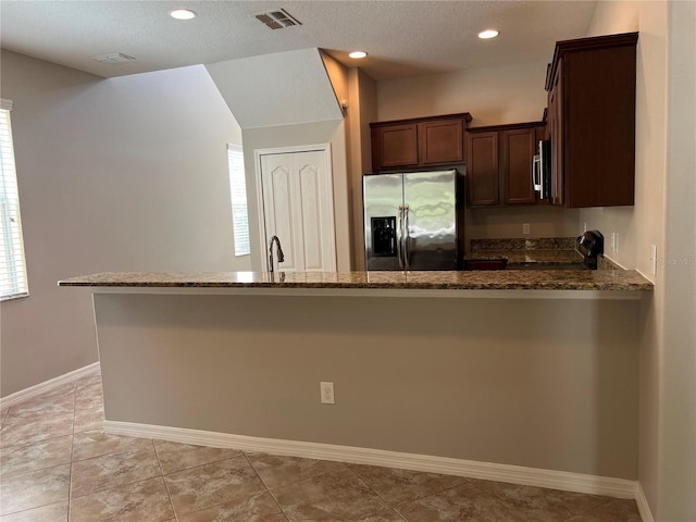 kitchen featuring a textured ceiling, dark stone counters, kitchen peninsula, and stainless steel appliances