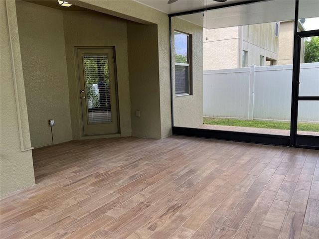 unfurnished sunroom featuring ceiling fan and a wealth of natural light