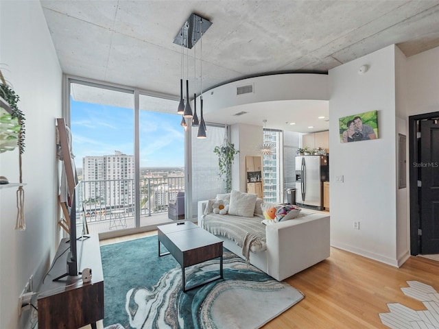 living room featuring a wall of windows, light hardwood / wood-style flooring, and plenty of natural light