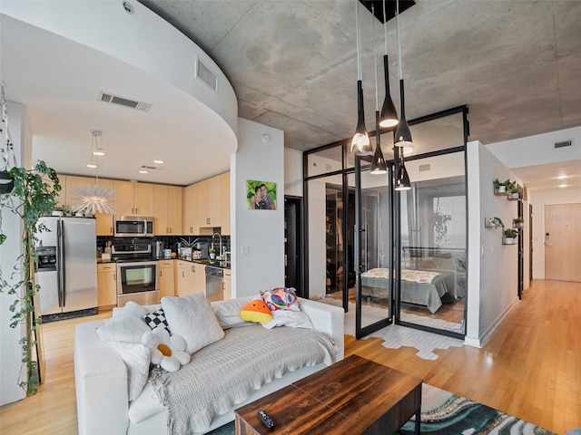 living room featuring light hardwood / wood-style flooring, a notable chandelier, and sink