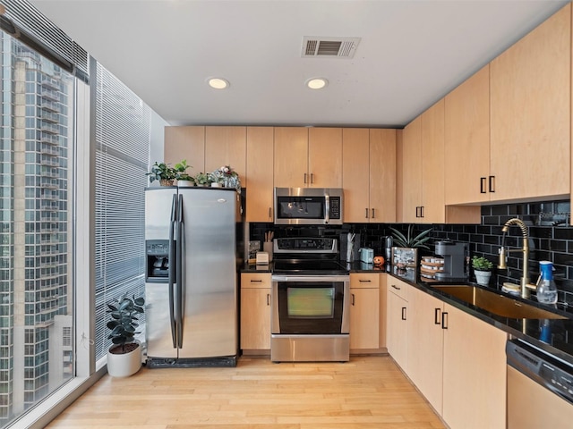 kitchen with light wood-type flooring, tasteful backsplash, sink, stainless steel appliances, and light brown cabinets