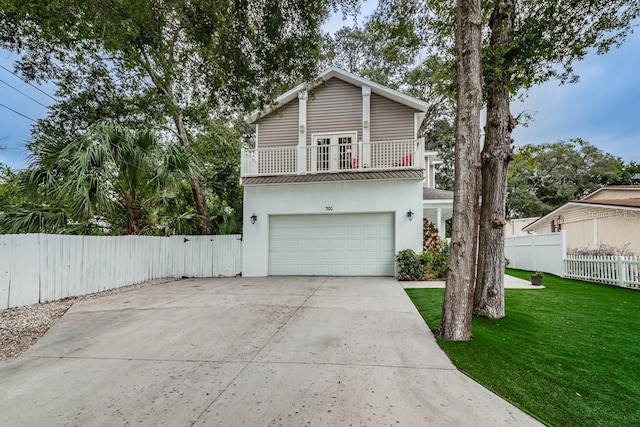 front of property featuring a front lawn, a garage, and a balcony