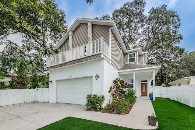 view of front facade featuring a front yard, a balcony, and a garage