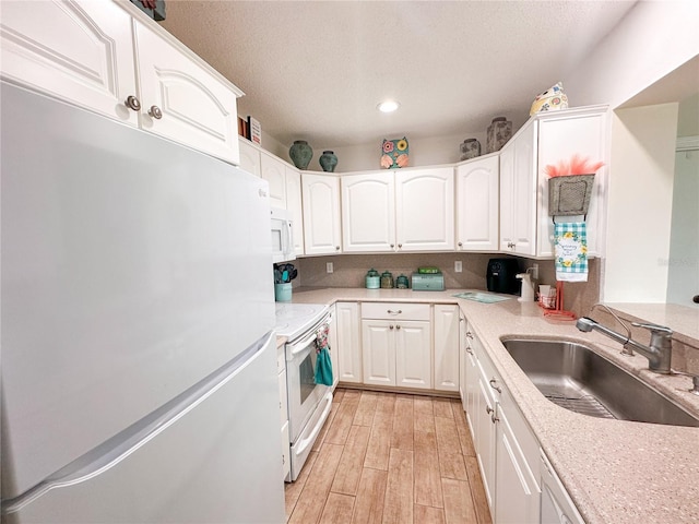 kitchen with white cabinets, white appliances, and sink