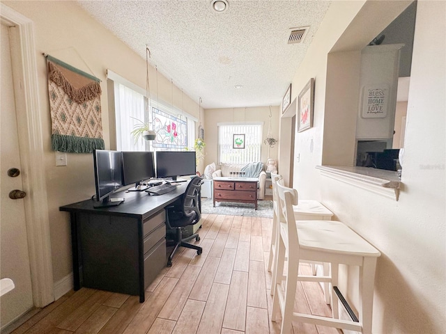 office area featuring a textured ceiling and light hardwood / wood-style flooring