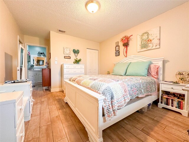 bedroom featuring a textured ceiling, a closet, and light hardwood / wood-style floors