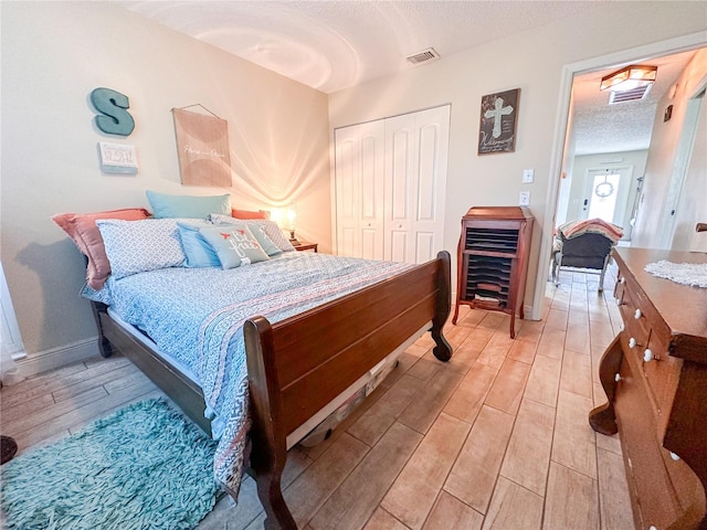 bedroom with light wood-type flooring, a textured ceiling, and a closet