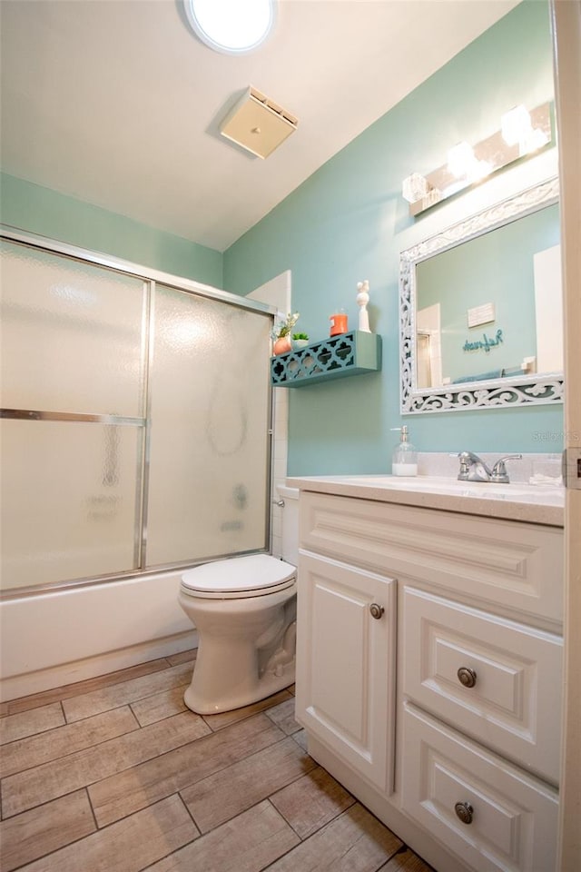 full bathroom featuring enclosed tub / shower combo, toilet, vanity, and hardwood / wood-style floors