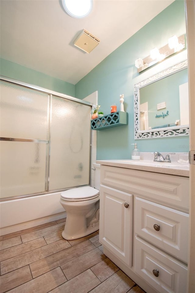 216 Gloucester Blvd Unit 216, Sun City Center, FL 33573 - bathroom featuring vanity, toilet, wood tiled floor, bath / shower combo with glass door, and vaulted ceiling