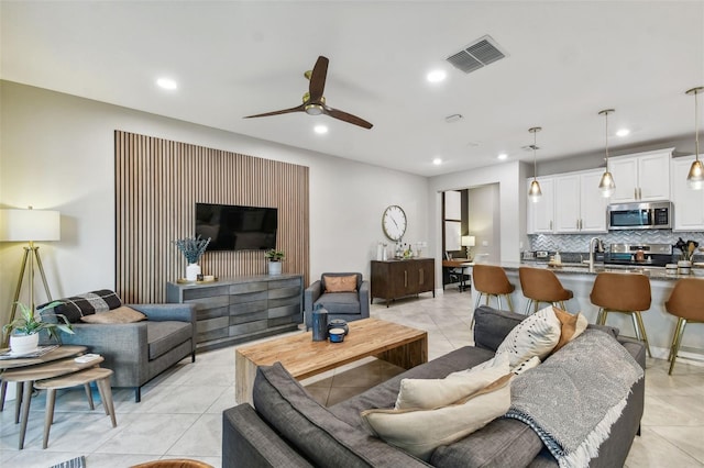 tiled living room with ceiling fan and sink