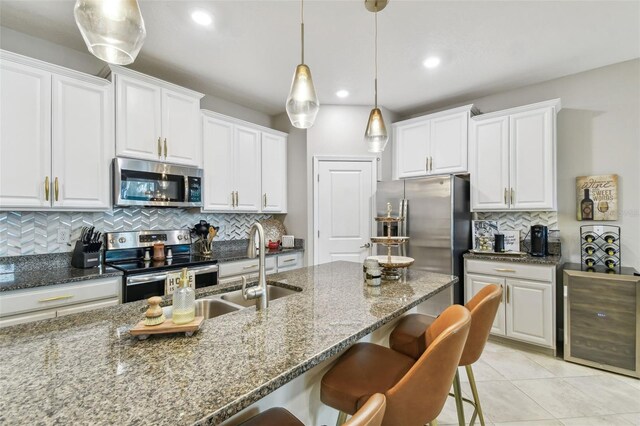 kitchen featuring stainless steel appliances, white cabinets, dark stone countertops, and backsplash