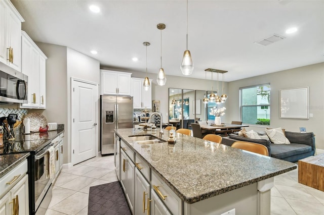 10012 Corso Milano Dr, Tampa, FL 33625 - kitchen featuring a kitchen island with sink, a sink, dark stone countertops, appliances with stainless steel finishes, and backsplash