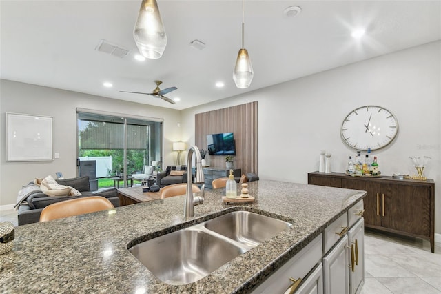 kitchen with dark stone countertops, ceiling fan, decorative light fixtures, and sink