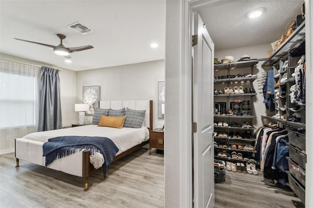 bedroom with a textured ceiling, light hardwood / wood-style floors, and ceiling fan