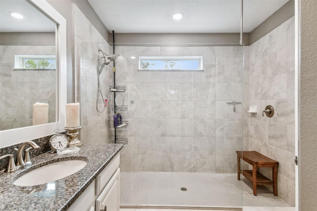 bathroom featuring vanity, a textured ceiling, and tiled shower