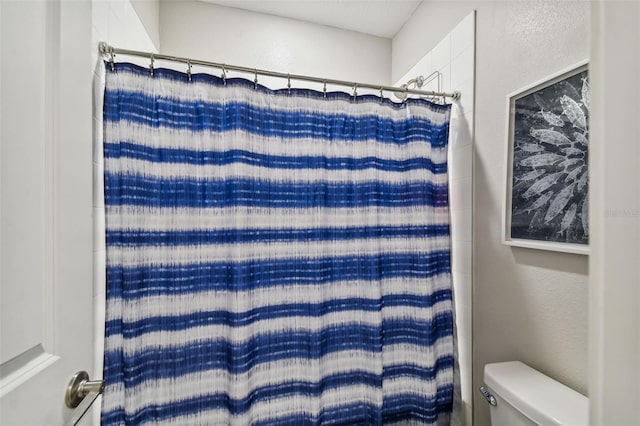 bathroom with toilet and a shower with curtain