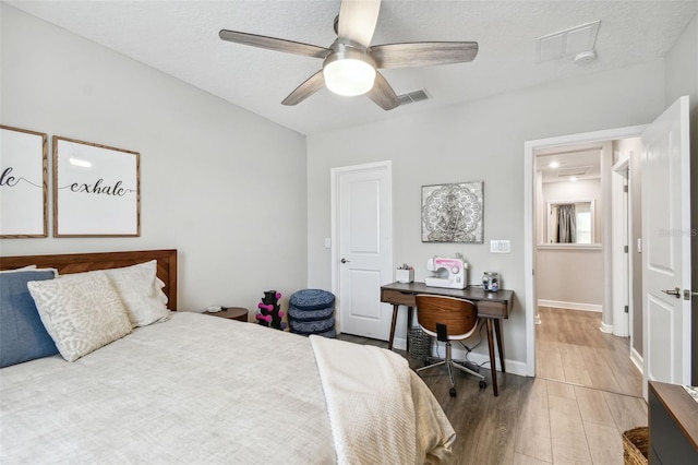 bedroom featuring ceiling fan, hardwood / wood-style flooring, and a textured ceiling