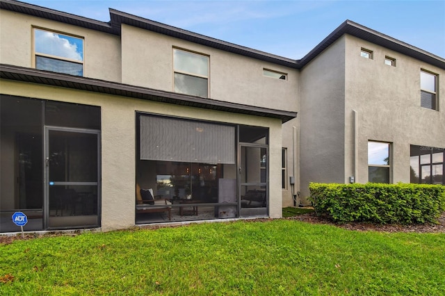 rear view of property featuring a lawn and a sunroom