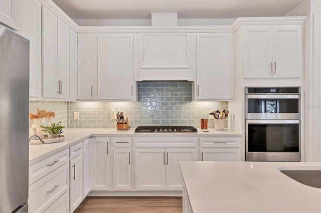 kitchen with stainless steel appliances, white cabinetry, and tasteful backsplash