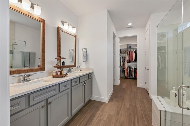 bathroom with wood-type flooring, a shower with shower door, and vanity