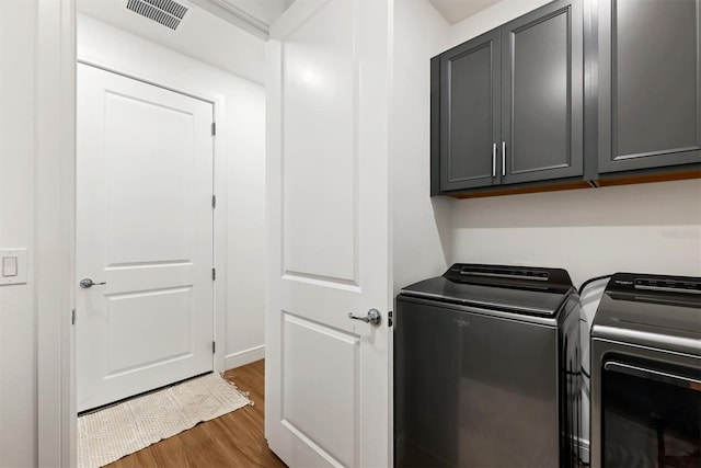 washroom featuring hardwood / wood-style flooring, cabinets, and separate washer and dryer