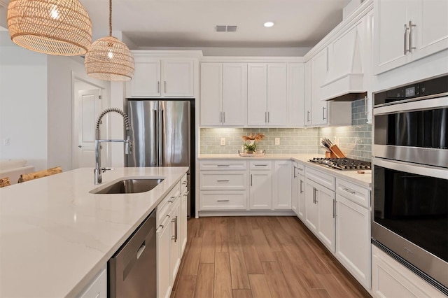 kitchen with sink, hanging light fixtures, white cabinets, and stainless steel appliances