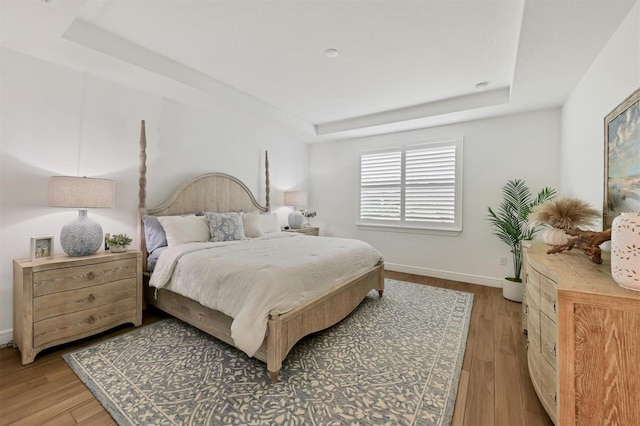 bedroom with hardwood / wood-style floors and a raised ceiling