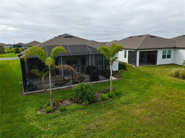 back of house featuring glass enclosure and a lawn