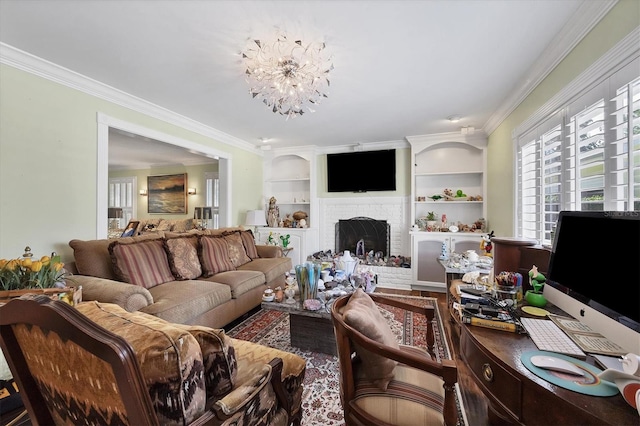 living room featuring a brick fireplace, built in features, an inviting chandelier, and crown molding