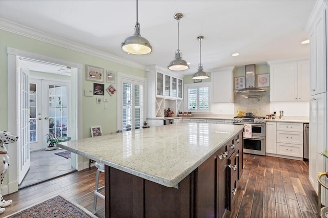 kitchen featuring french doors, wall chimney exhaust hood, white cabinetry, double oven range, and a kitchen island