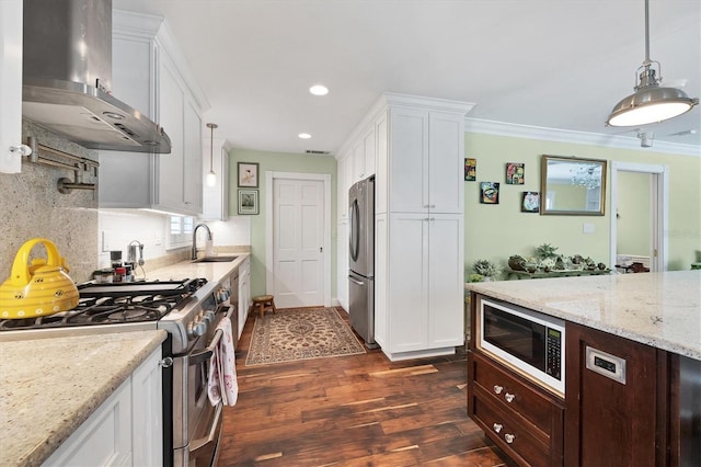 kitchen with a sink, white cabinets, appliances with stainless steel finishes, dark wood-style floors, and wall chimney exhaust hood