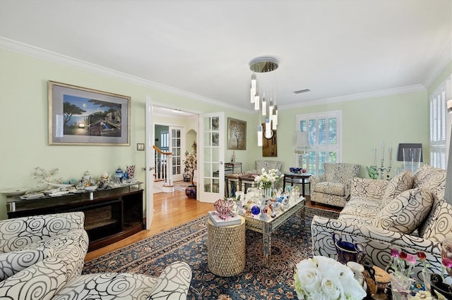 living area with wood finished floors, visible vents, stairs, french doors, and crown molding